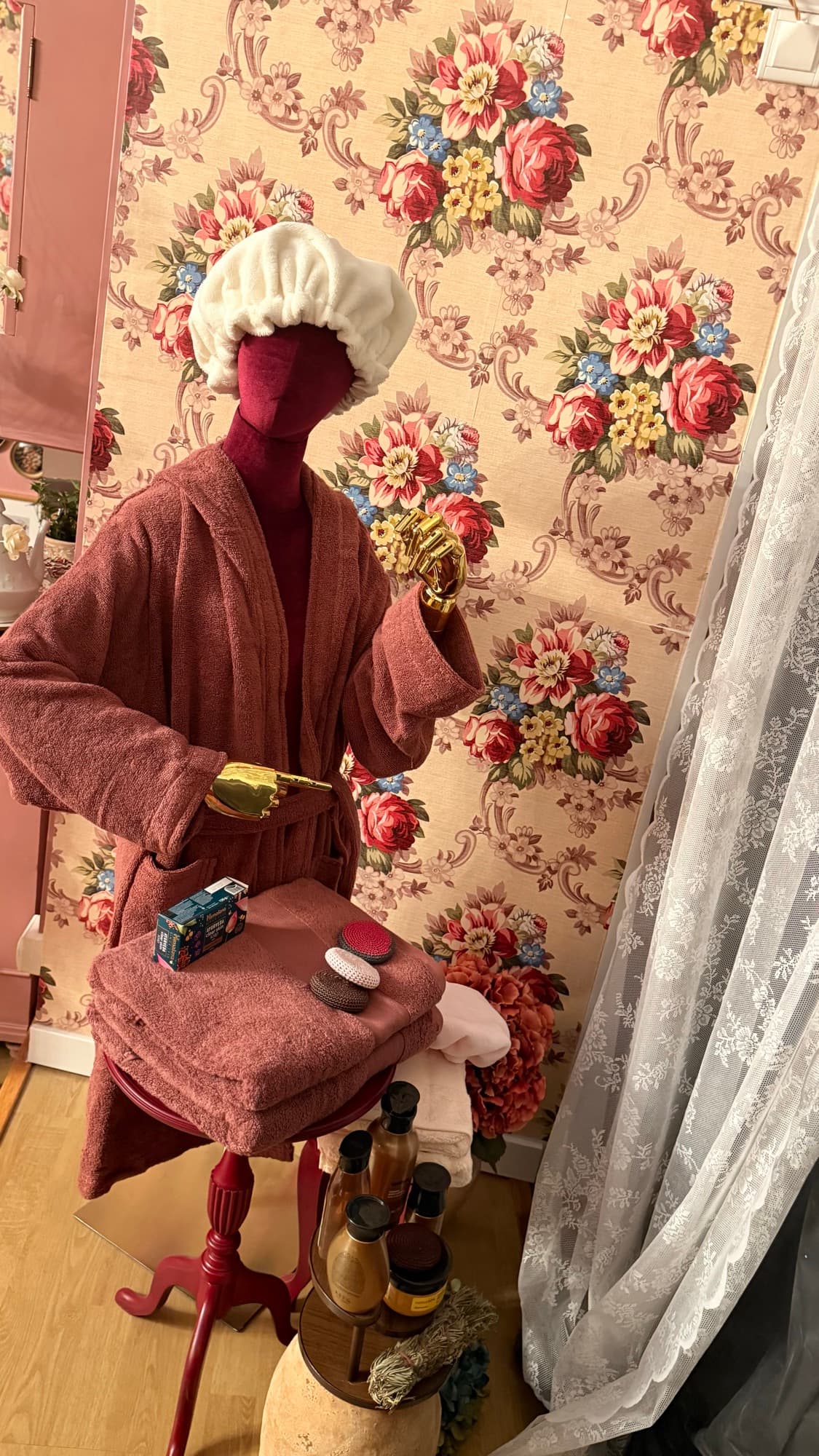 Coin bien-être : peignoir, serviettes et soins devant un papier peint à fleurs
