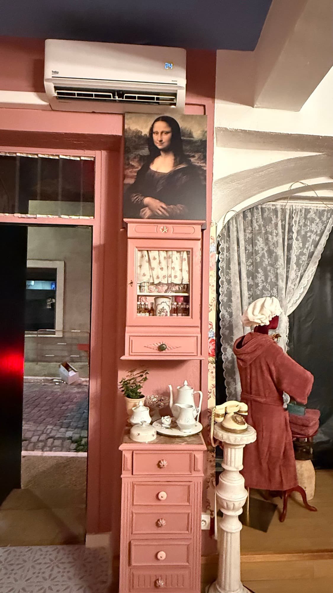 Entrée de l'institut : meubles peints en rose, service à thé en porcelaine et téléphone ancien