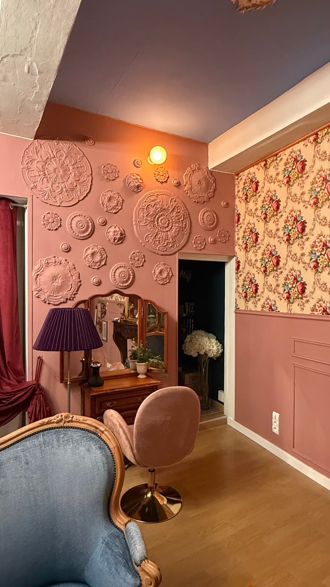 Salon de l'institut ANMA : murs vieux rose ornés de rosaces, coiffeuse en bois et fauteuil de velours
